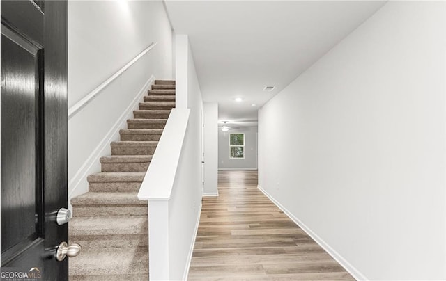 staircase with wood-type flooring and ceiling fan