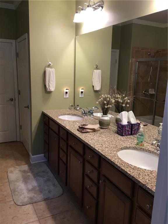 bathroom with crown molding, vanity, tile patterned flooring, and walk in shower