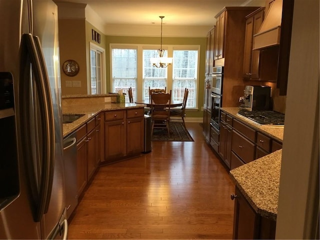 kitchen featuring pendant lighting, light stone counters, dark hardwood / wood-style flooring, and stainless steel appliances