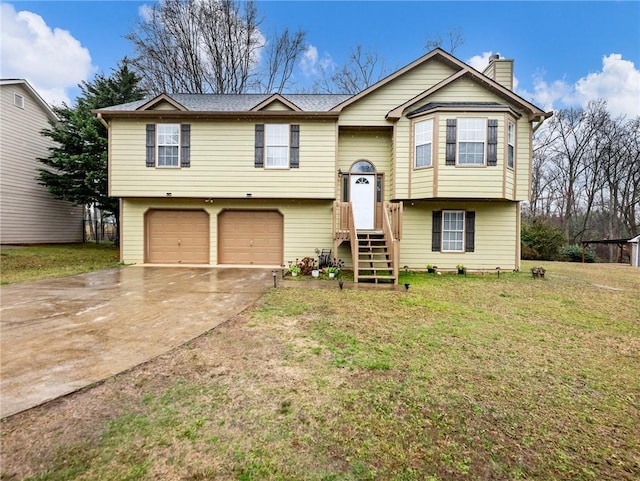 split foyer home featuring a garage, driveway, a chimney, and a front yard