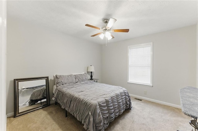 carpeted bedroom featuring visible vents, a textured ceiling, a ceiling fan, and baseboards