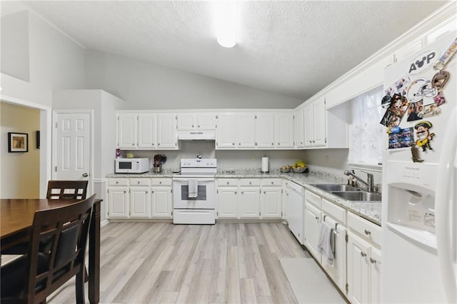 kitchen with under cabinet range hood, vaulted ceiling, white cabinets, white appliances, and a sink