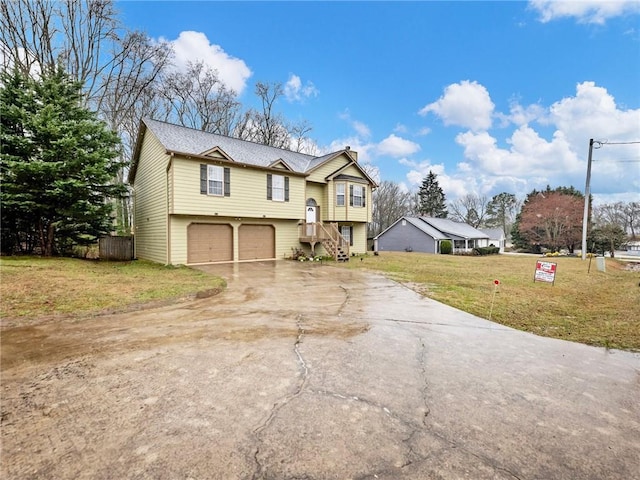 raised ranch featuring concrete driveway, an attached garage, and a front yard