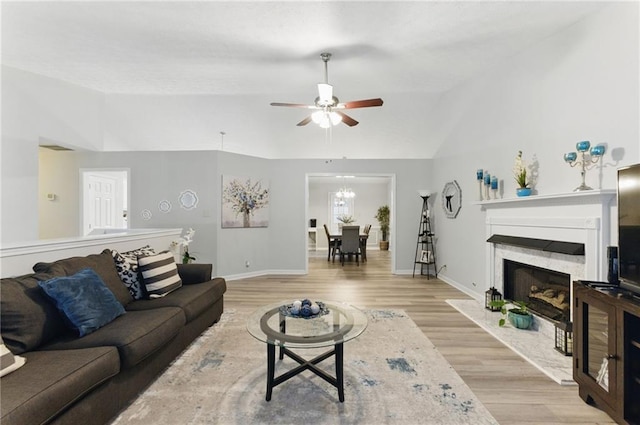 living room featuring light wood-type flooring, lofted ceiling, baseboards, and a high end fireplace