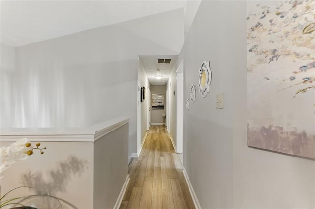 hallway with visible vents, baseboards, and light wood-style flooring