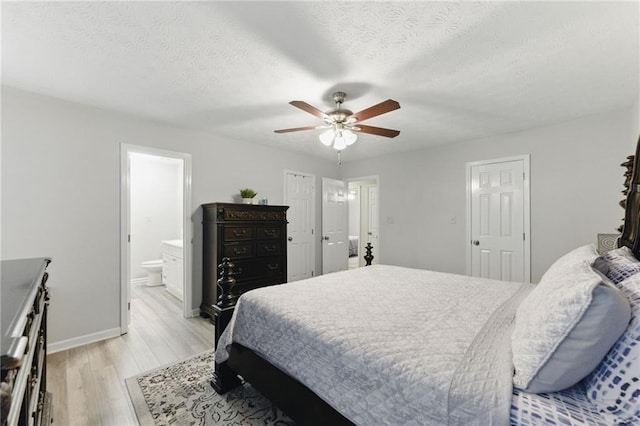 bedroom featuring baseboards, light wood-style flooring, ensuite bathroom, a textured ceiling, and a ceiling fan