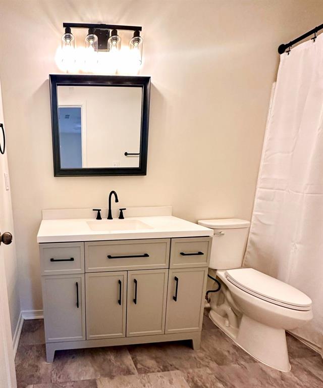 bathroom with vanity, toilet, and curtained shower