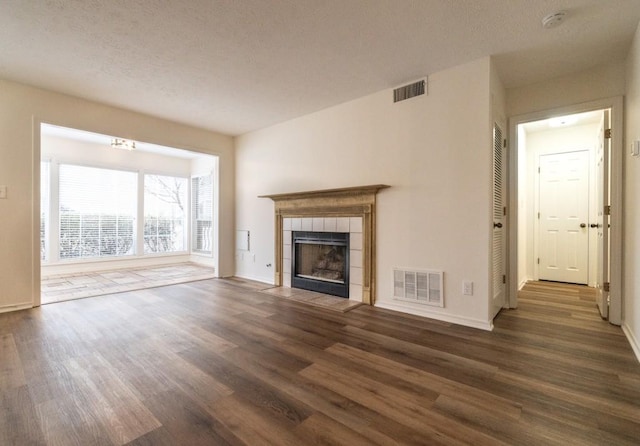 unfurnished living room featuring a tile fireplace and dark wood-type flooring