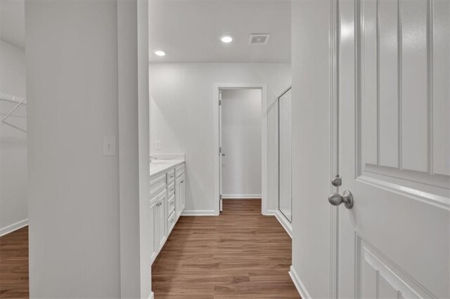 bathroom with baseboards, wood finished floors, vanity, and recessed lighting