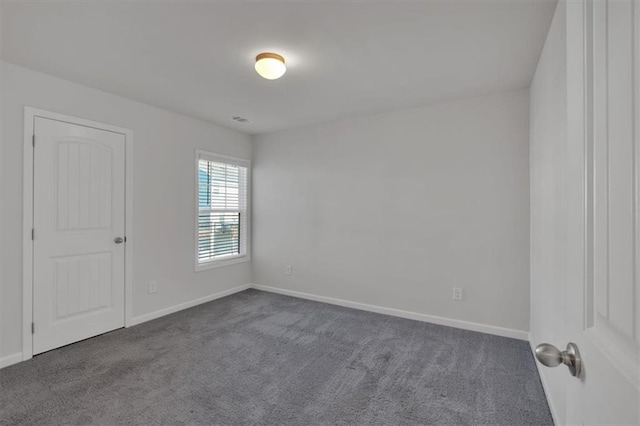 empty room with visible vents, baseboards, and dark colored carpet