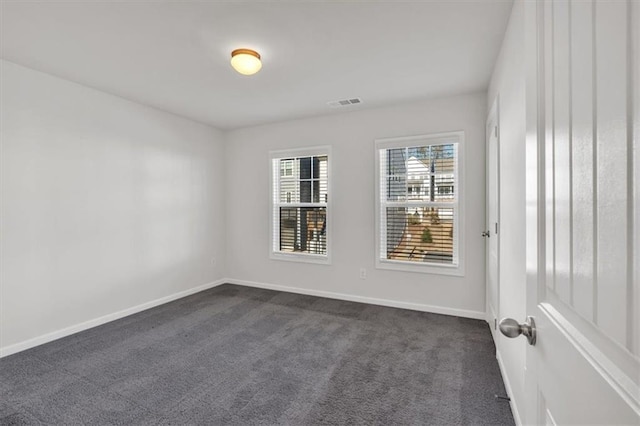 unfurnished room featuring visible vents, dark carpet, and baseboards