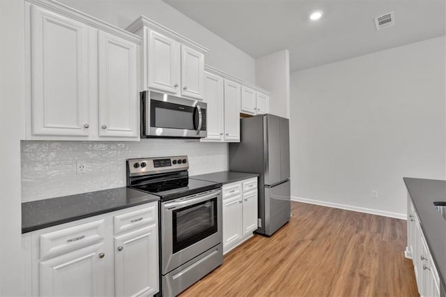 kitchen with dark countertops, white cabinetry, visible vents, and appliances with stainless steel finishes