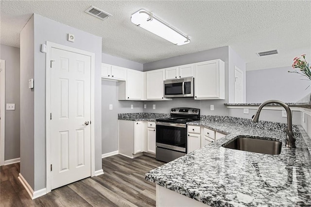 kitchen featuring stainless steel appliances, visible vents, a sink, and light stone counters