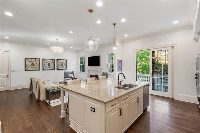 kitchen featuring hanging light fixtures, a breakfast bar area, a kitchen island with sink, stainless steel dishwasher, and sink