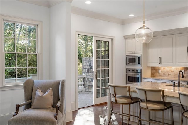 kitchen with decorative backsplash, hanging light fixtures, sink, light stone countertops, and appliances with stainless steel finishes