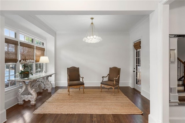 sitting room with ornamental molding, an inviting chandelier, and dark hardwood / wood-style floors