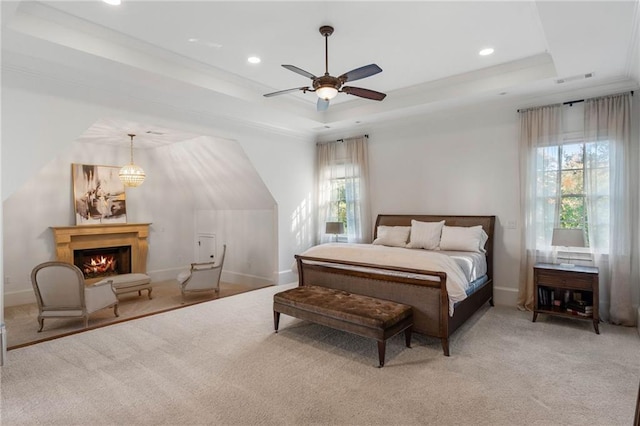 bedroom with light carpet, multiple windows, ceiling fan with notable chandelier, and a raised ceiling