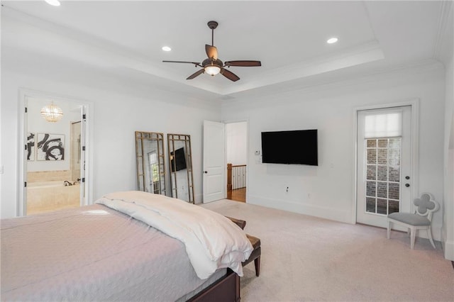 bedroom with multiple windows, ceiling fan, a tray ceiling, ensuite bathroom, and light colored carpet