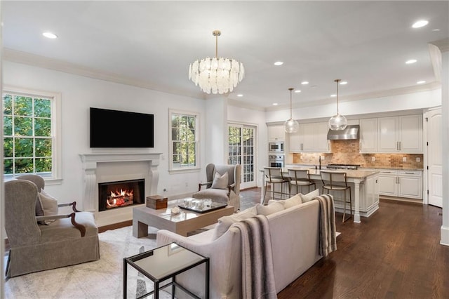 living room with a wealth of natural light, crown molding, a notable chandelier, and dark hardwood / wood-style flooring