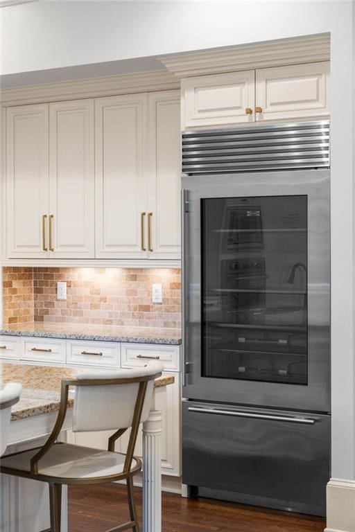 interior space featuring decorative backsplash, light stone countertops, beverage cooler, and dark hardwood / wood-style flooring