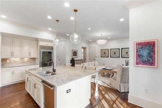 kitchen featuring appliances with stainless steel finishes, sink, dark hardwood / wood-style flooring, hanging light fixtures, and a center island with sink