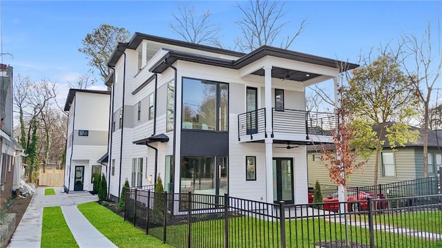 view of front of property with a balcony, ceiling fan, and a front lawn