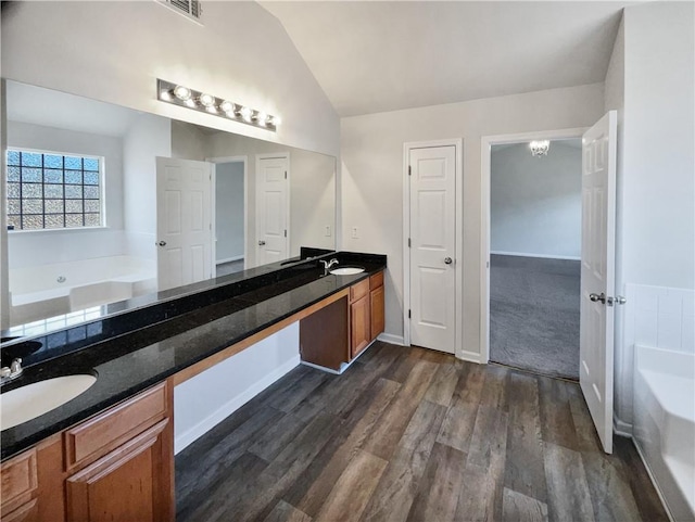 bathroom with vanity, a bath, vaulted ceiling, and hardwood / wood-style floors