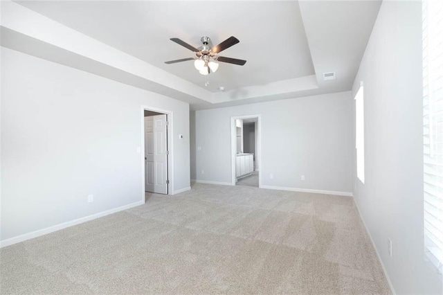 unfurnished room featuring light carpet, ceiling fan, and a tray ceiling