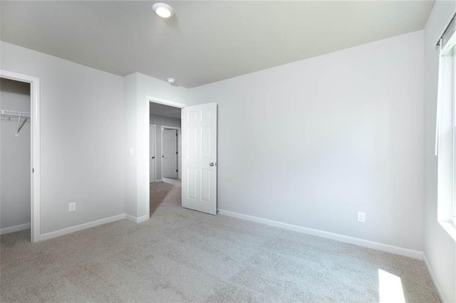 unfurnished bedroom featuring light carpet and a closet