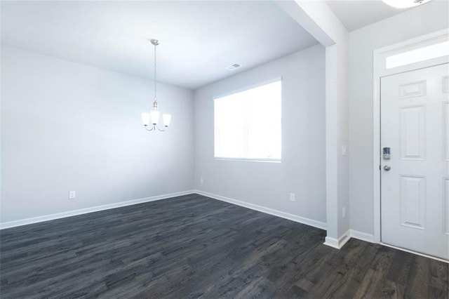 foyer with dark wood-type flooring and an inviting chandelier