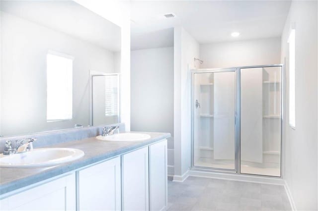 bathroom featuring a shower with shower door and vanity