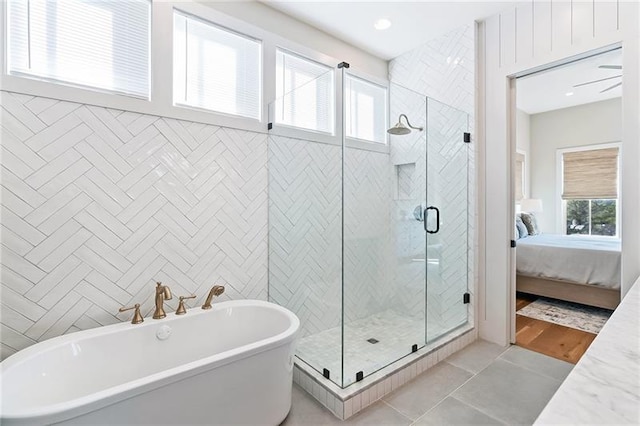 ensuite bathroom featuring a wealth of natural light, a stall shower, ensuite bathroom, and a freestanding tub