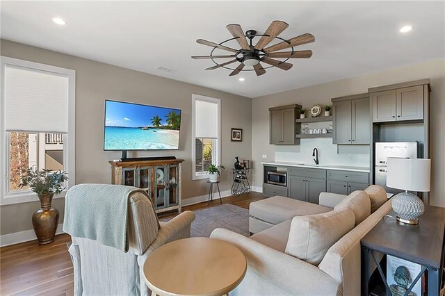 living room with ceiling fan, sink, a wealth of natural light, and light hardwood / wood-style flooring