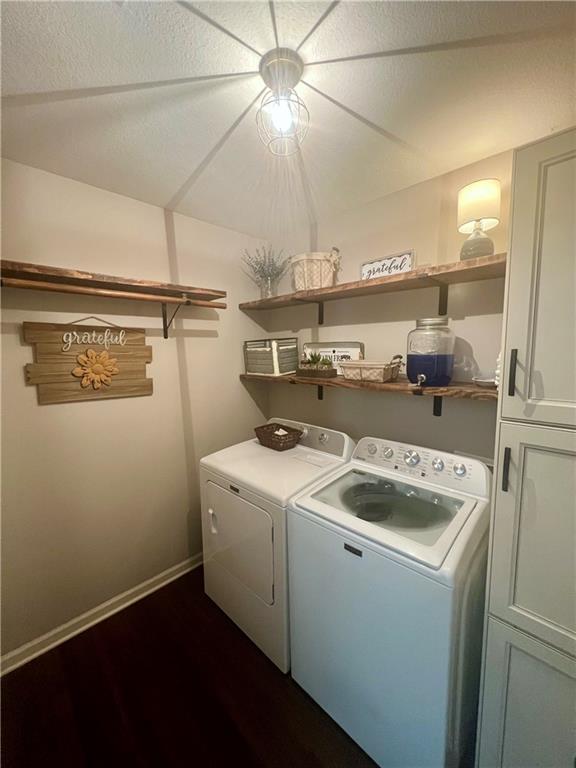 laundry room featuring separate washer and dryer, baseboards, dark wood finished floors, and cabinet space