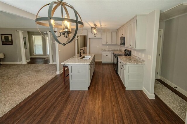 kitchen featuring light stone countertops, a sink, white cabinets, black appliances, and a chandelier
