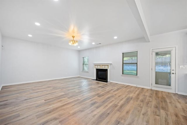 unfurnished living room with beamed ceiling, an inviting chandelier, and light hardwood / wood-style floors