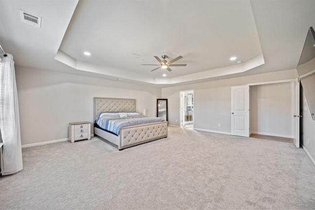 carpeted bedroom featuring a tray ceiling and ceiling fan