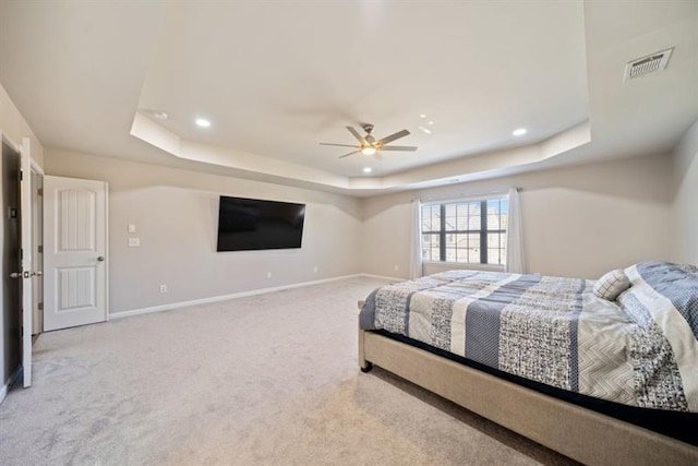 bedroom featuring ceiling fan, a tray ceiling, and light colored carpet