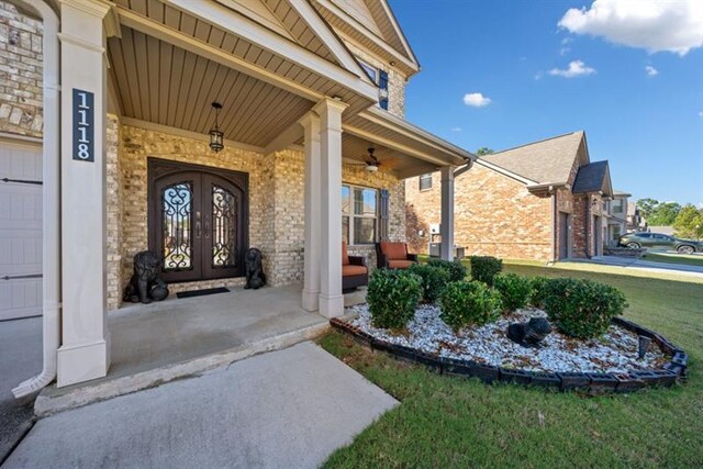 doorway to property with covered porch, french doors, and a lawn