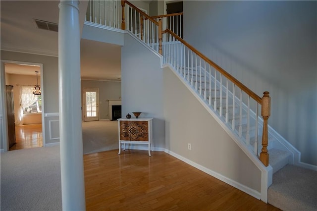 stairway featuring crown molding, visible vents, ornate columns, and wood finished floors