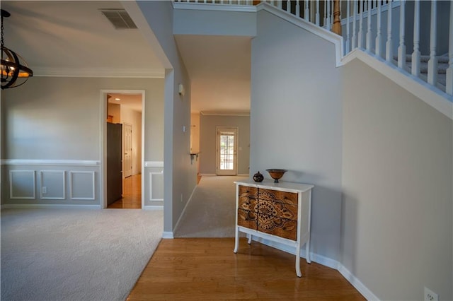 interior space featuring visible vents, an inviting chandelier, crown molding, wood finished floors, and stairs