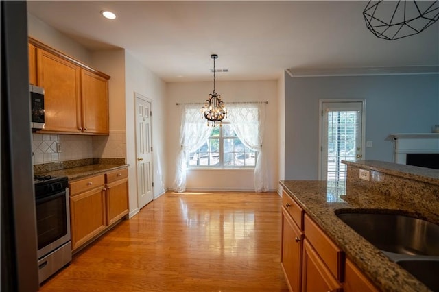 kitchen with brown cabinetry, light wood finished floors, plenty of natural light, and stainless steel appliances