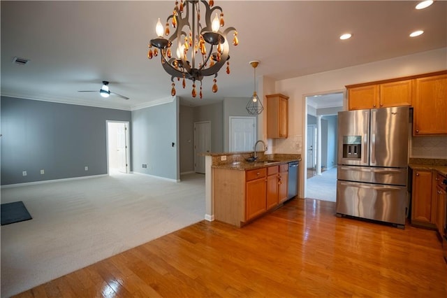 kitchen with visible vents, a sink, a peninsula, ceiling fan with notable chandelier, and stainless steel appliances