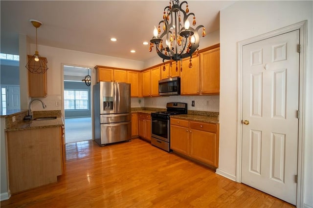 kitchen featuring a sink, decorative backsplash, a notable chandelier, and stainless steel appliances