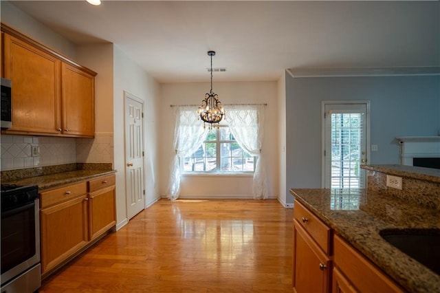 kitchen with baseboards, a chandelier, brown cabinetry, appliances with stainless steel finishes, and light wood finished floors