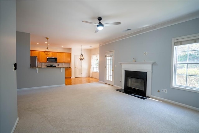 unfurnished living room featuring a wealth of natural light, visible vents, light colored carpet, and baseboards