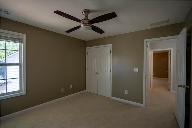 unfurnished bedroom with a closet, light colored carpet, and visible vents