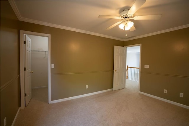 empty room featuring light colored carpet, baseboards, crown molding, and ceiling fan