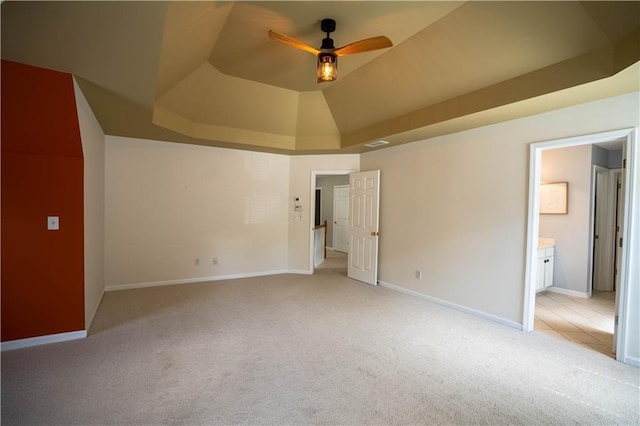 unfurnished bedroom featuring light carpet, visible vents, baseboards, and a raised ceiling