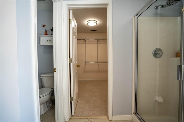 bathroom featuring visible vents, toilet, a walk in closet, a stall shower, and baseboards